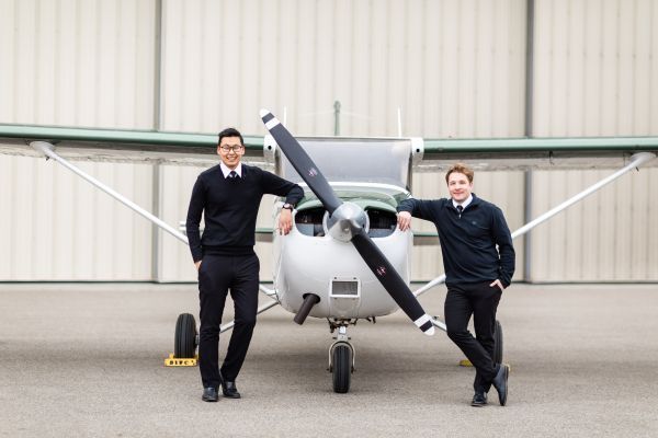 Two students beside a small plane