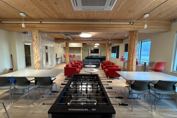 Student common room with foosball table, TV, and seating under wood-beam ceilings.