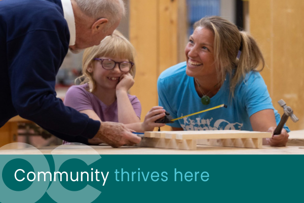 Camp OC coordinators with a young camper in the carpentry shop.