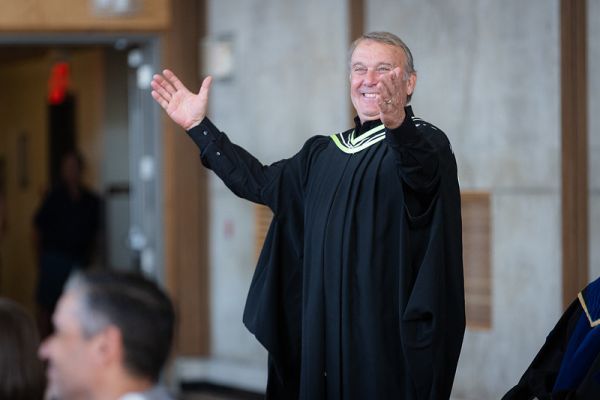 Stephen Speers with a big smile and his hands in the air at a recent Convocation ceremony.