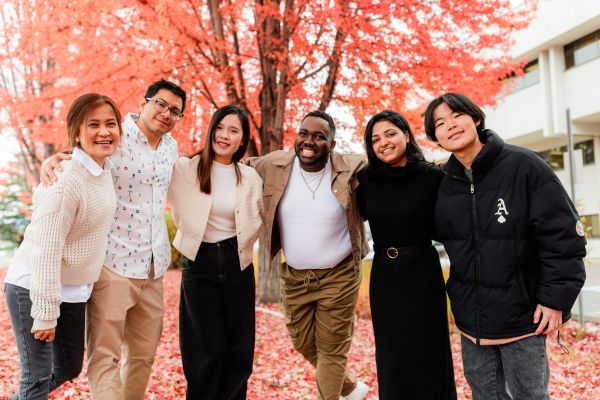 Students posing in front of fall leaves