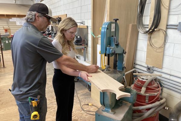 female listening to instructions from Carpentry Instructor on how to use saw