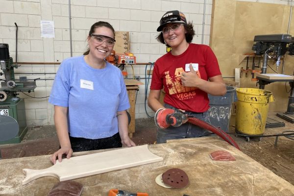 two females excited about carpentry and working on a wooden charcuterie board