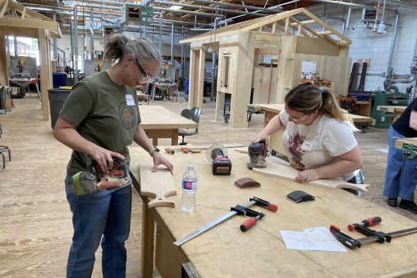 two females work together on their work projects at a bench in the carpentry shop