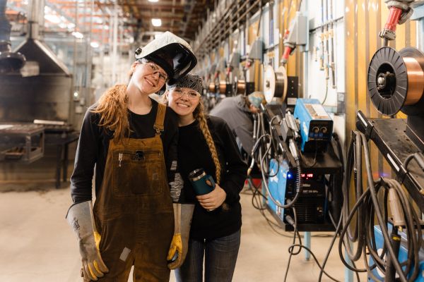 Two trades students posing in front of machinery