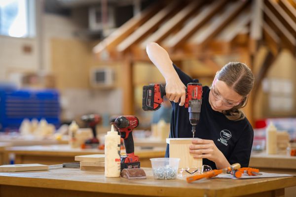 A trades student using a drill