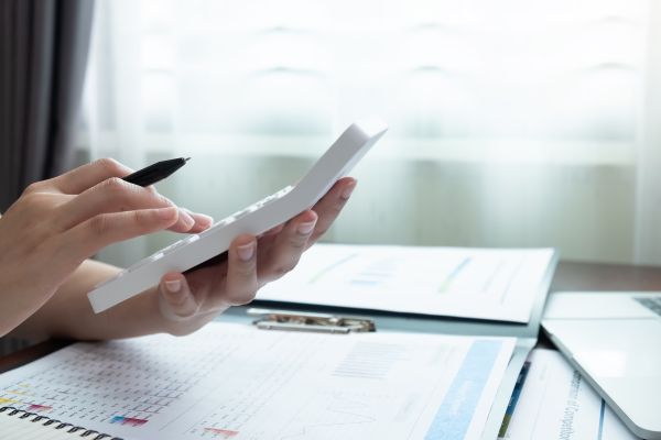 Close-up of hands using a calculator with financial documents and charts on a desk