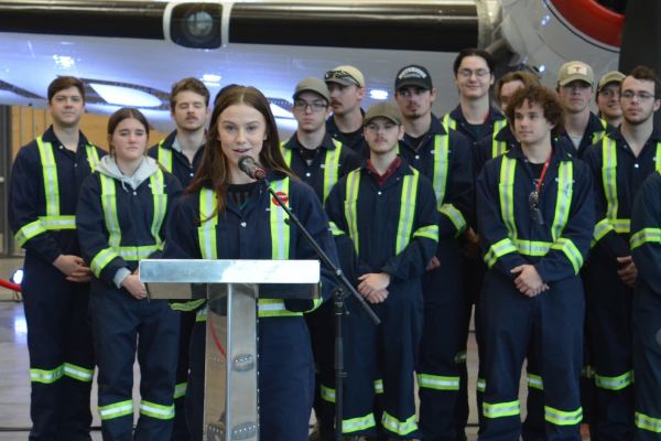 students wearing coveralls stand smiling