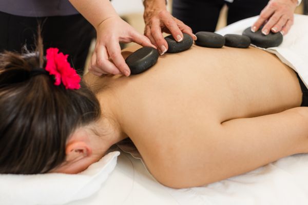 Hot stone massage in progress with smooth black stones placed along a client’s back on a treatment table