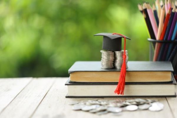 grad cap on top of money and books
