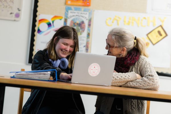 Student and teacher working on a laptop together