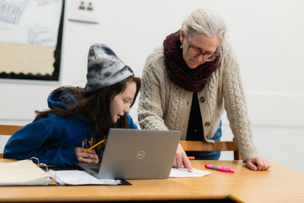 Teacher and student working on a laptop together