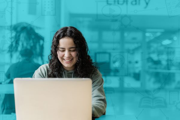 Learner working on laptop outside the library.