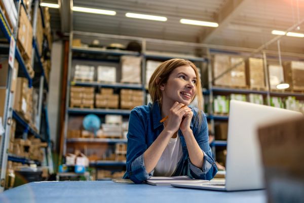 Female entrepreneur using laptop in a warehouse