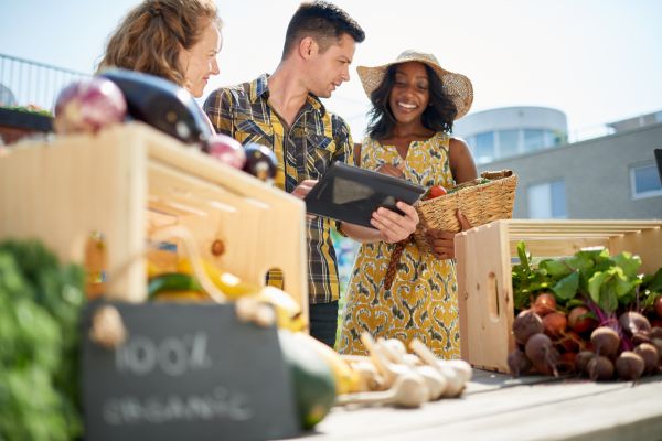 riendly woman tending an organic vegetable stall at a farmer's market