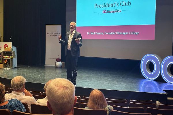 Photo of Dr. Neil Fassina onstage at the OC Foundation President's Club Happy Hour