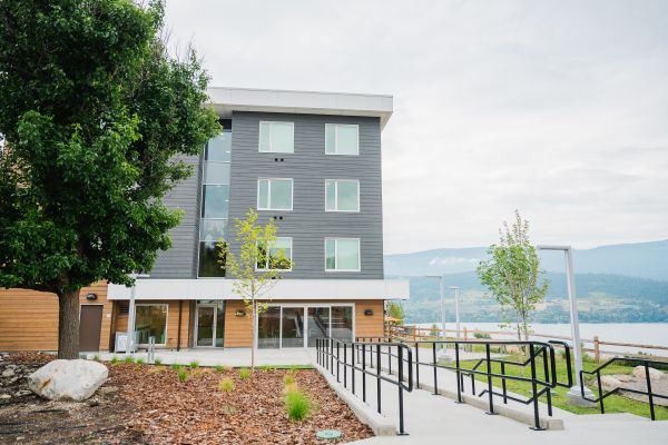 Exterior view of the student housing building overlooking the lake and surrounding Okanagan landscape.