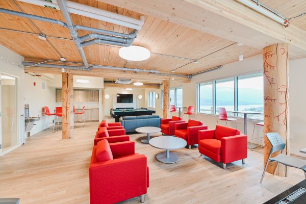 Large games room featuring rows of red chairs, a couch, a pool table, a TV, tall tables with bar-height chairs, and a sink with surrounding cabinetry, offering a spacious area for relaxing, socializing, and entertainment.