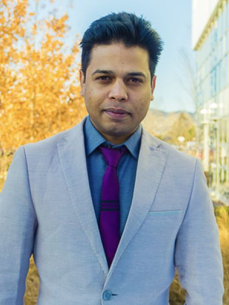 Amir with blue suit with fall trees in the background