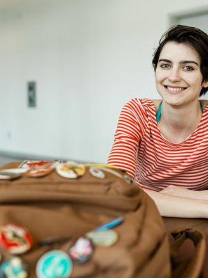Arts student sitting at a table with a backpack in front of her.