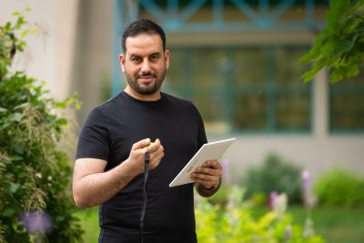 Omar Algiasena, a graduate of OC's Advanced GIS Certificate smiling at the camera and holding a tablet
