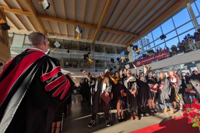 Students throw their graduation hats in the air while OC President Neil Fassina looks on.