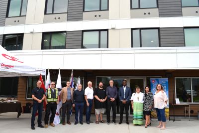 Dignitaries line up for a photo in front of the Penticton campus housing building.