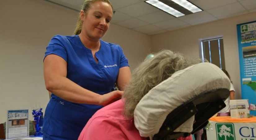 client sitting in massage chair being massaged by a practitioner 