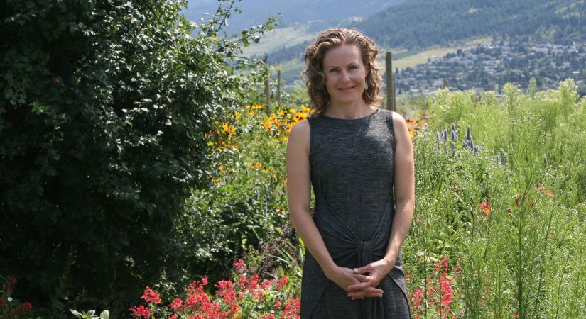 Creative Writing Professor Kerry Gilbert stands in a field of flowers