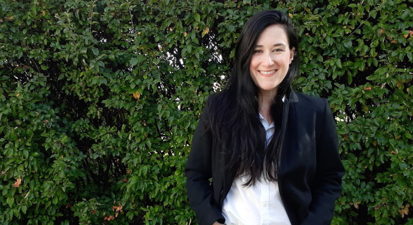 Sociology Professor Mary Hanlon stands in front of a green hedge