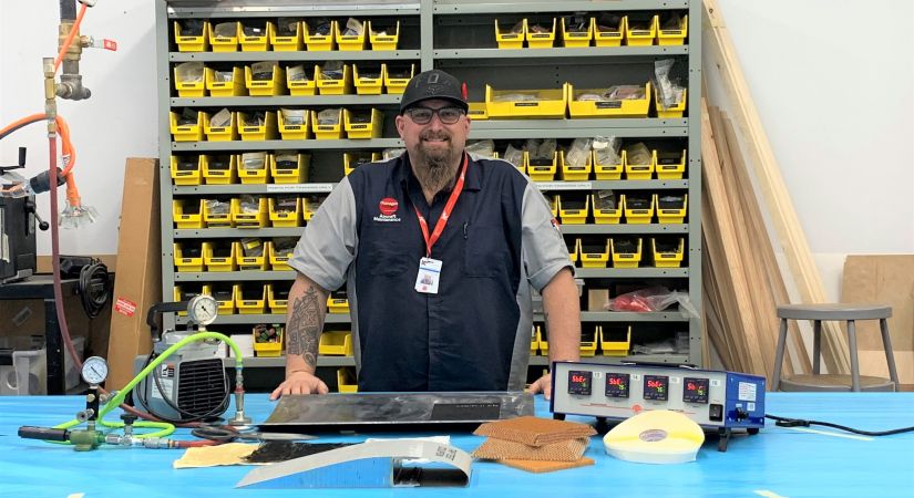 Aircraft Maintenance Engineer Patrick Thomson stands behind a table of equipment used in structures training.