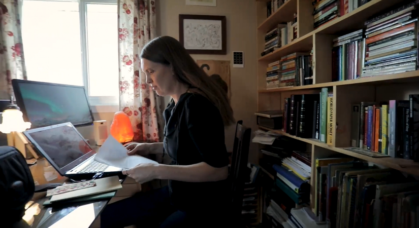 English Professor Hannah Calder reads while sitting in her home office by a window