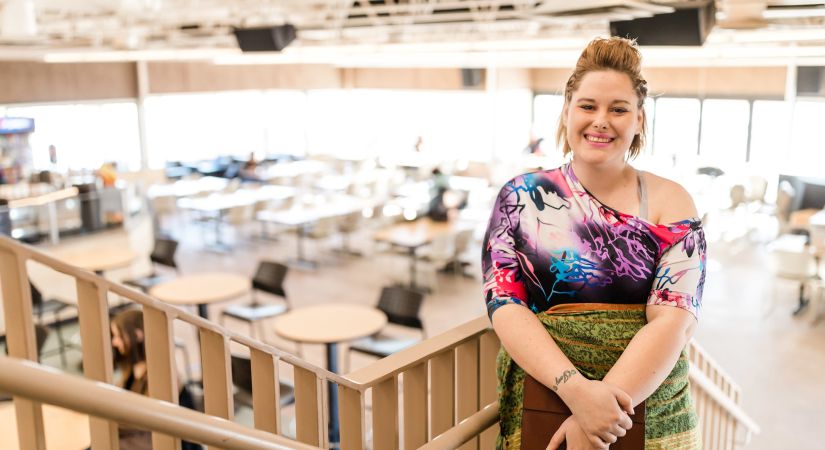 Vernon student with a colourful shirt stands in front of the stairs overlooking the Kal View Cafe.