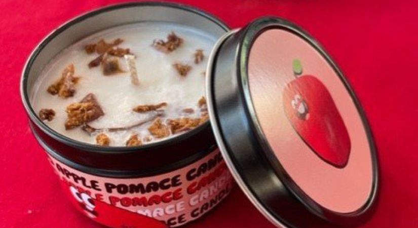 Candle in a jar open to show wick displayed on a red table