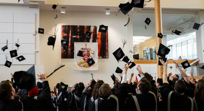 Photo of graduates tossing their graduation caps in the air