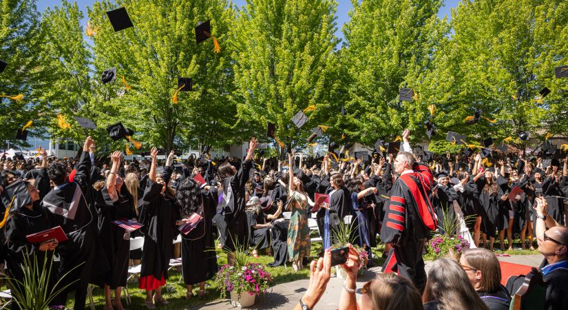 Graduates throw their hats in the air at the Kelowna OC convocation and commencement ceremony.