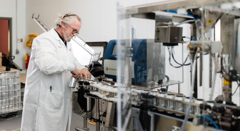 A lab technician at BC BTAC works with a new test batch canning line.