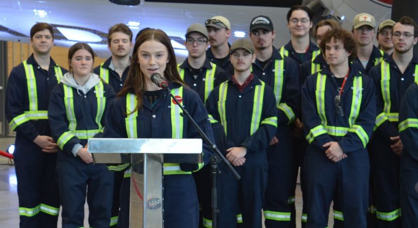 students wearing coveralls stand smiling