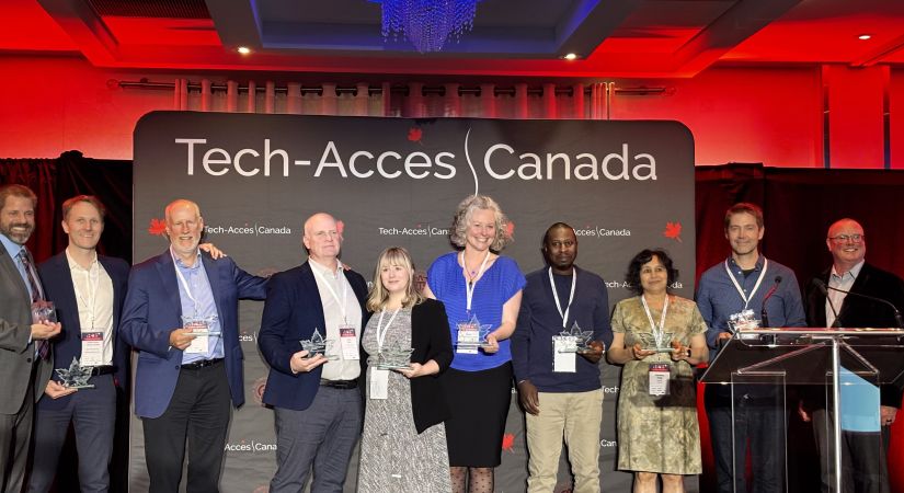 Tech-Access Canada award recipients stand together holding their trophies and smiling.