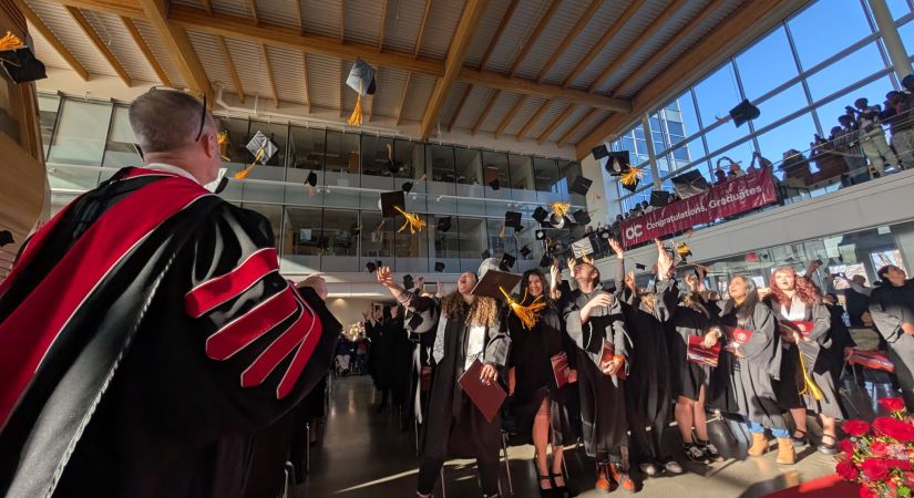 Students throw their graduation hats in the air while OC President Neil Fassina looks on.