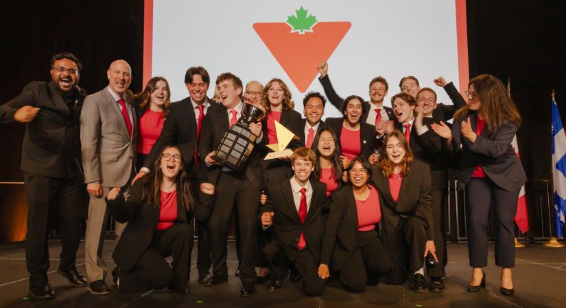 Enactus Okanagan Team celebrating on stage after winning the Enactus National Championship, holding trophies and cheering together.