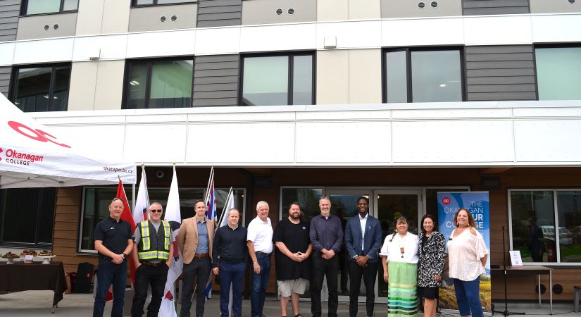 Dignitaries line up for a photo in front of the Penticton campus housing building.